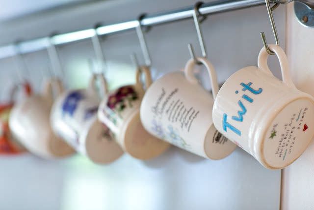 چیدمان لیوان های دسته دار و ماگ از قلاب های اس شکل از آیوز حوله در آشپزخانه