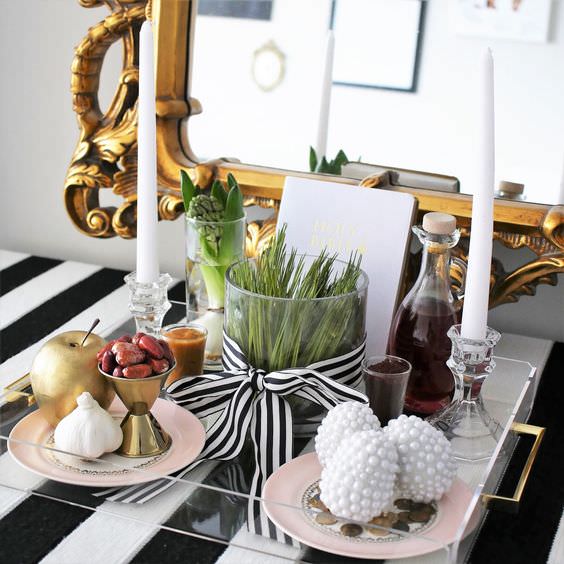 چیدمان سفره هفت سین مدرن روی میز کنسول با سینی شیشه ای و ظروف طلایی و بلوری