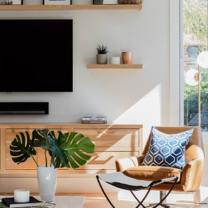 تزیین دیوار پشت تلویزیون با نصب شلف چوبی و چیدمان قاب عکس