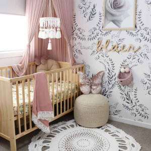 دکوراسیون اتاق نوزاد دختر سفید صورتی با پوستر دیواری طرح برگ و تور بالای تخت صورتی