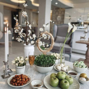 چیدمان سفره هفت سین مدرن روی میز جلو مبلی با ظروف تزئینی سفید