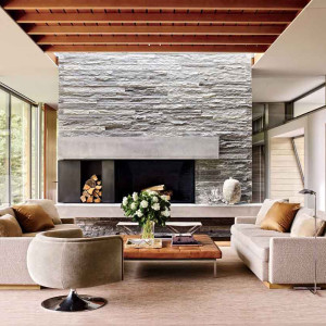 دیزاین نشیمن و پذیرایی مدرن با شومینه و دیوار سنگ آنتیک و مبلمان کرم طوسی