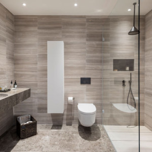 سرویس بهداشتی و حمام مدرن بزرگ با کاشی های کرم قهوه ای و اتاق دوش شیشه ای و توالت فرنگی وال هنگ