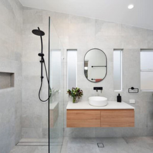 حمام مدرن با کاشی های طوسی روشن و اتاق دوش شیشه ای و روشویی کابینت دار بدون پایه