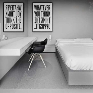 اتاق خواب طوسی و سفید و مشکی با دیوار و تخت طوسی، روتختی سفید و صندلی مشکی