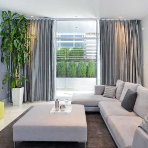 دکوراسیون طوسی و زرد نشمین با دیوار و مبل و پرده طوسی و پاف های زرد