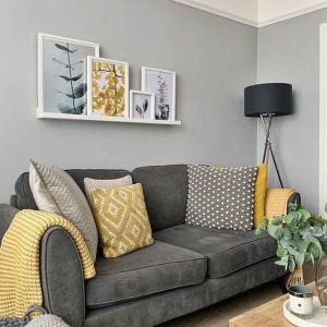 دکوراسیون طوسی و زرد نشیمن با دیوار و مبل طوسی و تابلو دکوری و کوسن زرد