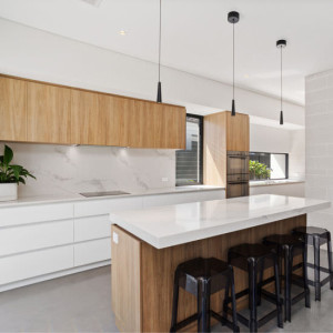 کابینت سفید و رنگ چوب روشن مات در آشپزخانه مدرن جزیره دار با بین کابینتی سنگ مرمر سفید