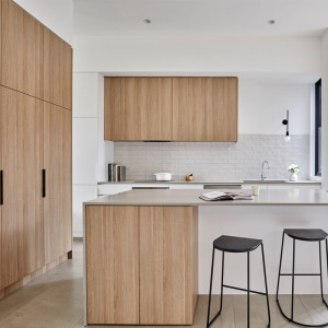 کابینت سفید و رنگ چوب روشن مات در آشپزخانه مدرن جزیره دار با بین کابینتی آجری