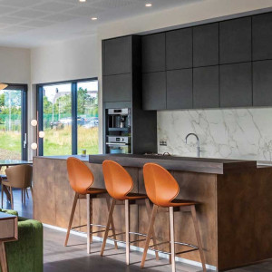 کابینت طوسی تیره ام دی اف مات در آشپزخانه با جزیره قهوه ای چوبی و بین کابینتی طرح سنگ مرمر سفید