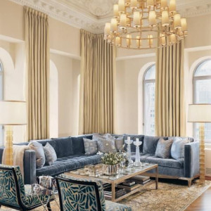 دکوراسیون آبی طلایی هال و پذیرایی نئوکلاسیک با دیوارهای کرم و مبل آبی و لوستر طلایی